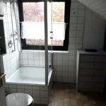 Badezimmer mit Dusche, Toilette und Schrank. Fenster mit Vorhang.