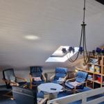 Ein Wohnzimmer mit Sitzgelegenheiten, Bücherregal und Dachfenster.