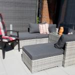 Terrasse mit Sitzgruppe, Liege und Stuhl mit kariertem Kissen.