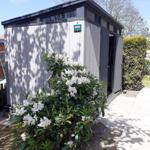 Gärtnerhaus mit blühendem Strauch und gepflastertem Weg.