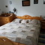 Schlafzimmer mit Holzbett, Nachttisch und Schrank an weißen Wänden.