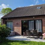 Haus mit Terrasse, Garten und Blumen. Durchgangstür und Fenster sind sichtbar.