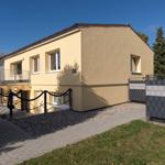 Zweistöckiges Haus mit Balkon, gepflastertem Weg und Grünfläche.