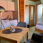 Küche, Essbereich und Schlafzimmer in einer Wohnung mit Holzdecke und grünem Teppichboden.