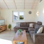 Wohnzimmer mit Sofa, Couchtisch und Fernseher. Holzdecke und Fenster.