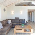 Wohnzimmer mit Sofa, Couchtisch und Balkon. Hölzerner Boden und weiße Wände.
