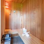 Sauna mit Holzwand, Bank, Steinkessel und Badematten.
