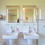 Zwei Waschbecken mit Spiegeln und Dusche im Badezimmer.