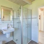 Badezimmer mit Dusche, zwei Waschbecken und Spiegeln mit Beleuchtung.