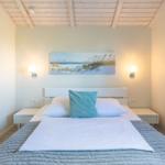 Schlafzimmer mit Bett, Wandbild und Stehlampe an den Wänden.