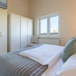 Schlafzimmer mit Bett, Kleiderschrank und Fenster.