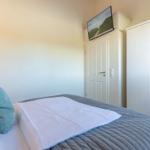 Schlafzimmer mit Bett, Kleiderschrank und Fernseher an der Wand.