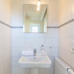 Badezimmer mit Waschbecken, Spiegel und Heizkörper an der Wand.