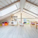 Kinderzimmer mit Spielküche, Tisch, Stühlen und Spielzeug unter Dachschrägen.