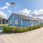 Blau gestrichenes Ferienhaus mit weißem Fensterrahmen und begrüntem Vorgarten.