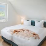 Schlafzimmer mit Doppelbett, Fenster und Nachttischen.