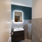 Badezimmer mit beleuchtetem Spiegel und Waschbecken.