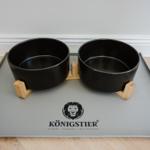 Zwei schwarze Futternäpfe auf einem grauen Untersetzer mit Markenlogo.