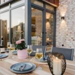 Terrasse mit gedecktem Tisch, Wein und Kerzen.