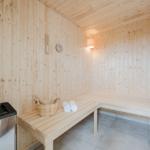 Sauna mit Holzbank, Thermometer und Wasserbucket.