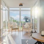 Lichter Raum mit Sitzgelegenheiten und Blick auf Garten.