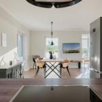 Esszimmer mit Holztisch, Stühlen und Küchenzeile