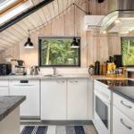 Kitchen with white cabinets, stone countertops, and view of forest.