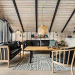 Living room with wooden ceiling, sofa, chairs, table, and rug.