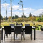 Deck with dining table and chairs, view of forest and meadow.