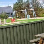Hinterhof mit Spielplatz, Holztisch und grünem Zaun. Im Hintergrund Haus und Bäume.