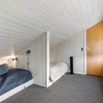 Zimmer mit zwei Betten, Holztür und Fenster mit Jalousie.
