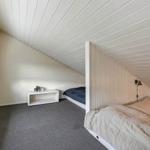 Zimmer mit zwei Betten, Fenster und weißem Schrank unter Dachschrägen.