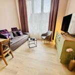 Wohnraum mit Sofa, Tisch, Stuhl und TV. Fenster mit Vorhängen.