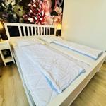 Schlafzimmer mit weißem Bett, floraler Wand und Nachttischen.