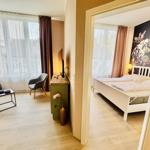 Wohnzimmer mit Sofa und Schlafzimmer mit Bett und Wandbild.