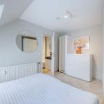 Schlafzimmer mit Dachschrägen, Bett, Spiegel und Schrank. Durchgang zur Bad.