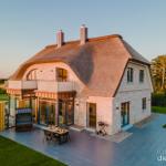 Modernes Haus mit Strohdach, Terrasse und Garten. Grill und Sitzgelegenheiten vorhanden.