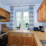 Küche mit Holzschränken, Fenster und Arbeitsfläche