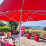 Terrasse mit rotem Sonnenschirm und Blick aufs Meer.