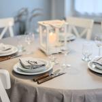 Runde Tisch mit Stühlen, Tischdecke, Geschirr und Kerzenleuchter.