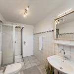 Badezimmer mit Dusche, Waschbecken und Toilette.