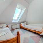 Zwei Betten unter Dachschrägen mit Dachfenster und Teppichboden.