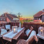 Terrasse mit Tisch, Stühlen und Laterne bei Sonnenuntergang.