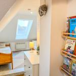 Schlafzimmer mit Dachschrägen und Bücherregal an der Wand.