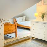 Schlafzimmer mit Holzbett, Schrank und Pflanzen unter Dachschrägen.