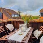 Terrasse mit Tisch, Stühlen und Blick auf Dächer.