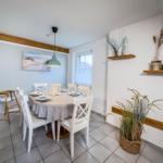 Esszimmer mit runden Tisch, weißen Stühlen und dekorativen Regalen an der Wand.