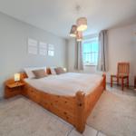 Schlafzimmer mit Holzbett, Spiegel und Kleiderschrank.