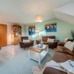 Wohnzimmer mit Kamin, Sofa, Sessel und Wandbildern