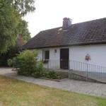 House with white facade, dark roof, and ramp to the entrance door.